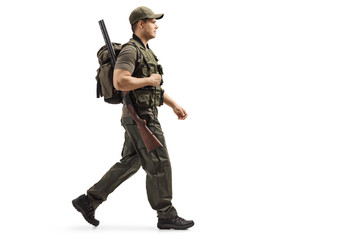 Naklejka premium Hunter walking and carrying a backpack and a shotgun