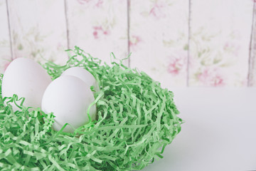 Naklejka na ściany i meble Easter white eggs in a nest on a flower background