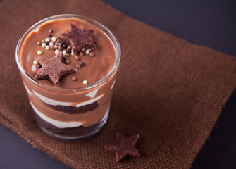 Chocolate dessert in glass jar on a table with wooden spoon. Top view.
