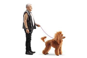 Mature punker standing with a red poodle on a leash