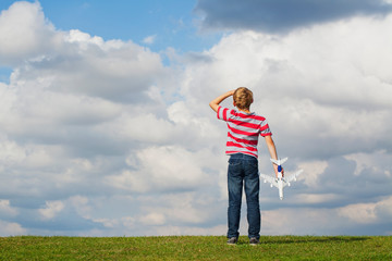 Boy holding model plane looking up to the sky