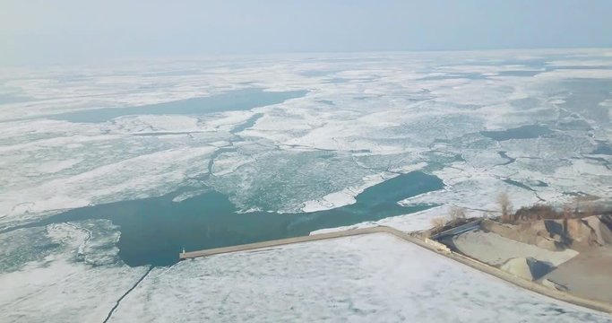 Aerial drone shot: the dock and the surroundings of Lake Erie (one of the Great Lakes of North America). Exploring a partially frozen body of water. Forward pedestal movement.