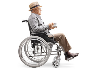 Obraz na płótnie Canvas Elderly man sitting in a wheelchair with a cup of coffee