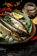 Food background. Fresh, raw fish with a swallow, lemon on a dark wooden background