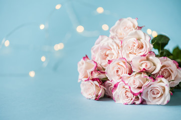 Coral roses on blue background with bokeh. Postcard concept. Happy Mother's Day, Women's Day or Birthday. Minimalism, selective focus, place for text.