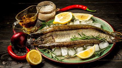 Delicious fresh fish on dark vintage background. Fish with aromatic herbs, spices and vegetables - healthy food, diet or cooking concept. top view