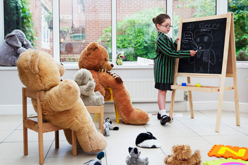 Young girl pretending to be a teacher to her teddy bears