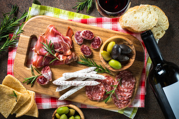 Antipasto - sliced meat, ham, salami, olives on dark stone table  top view.