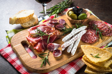 Antipasto delicatessen - sliced meat, ham, salami, olives on wooden board. 