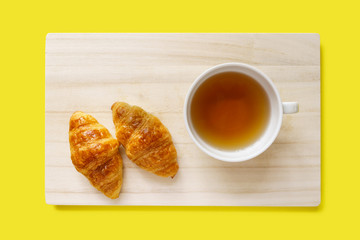 Croissant and a cup of tea on a wooden tray