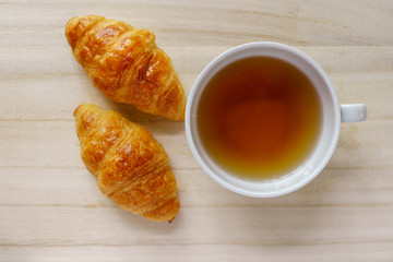 Croissant and a cup of tea on a wooden tray