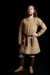 Redhead long-haired young man in casual clothes of the Viking era 