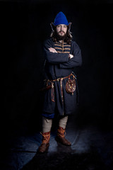 Young bearded man in a viking age Slavic hat and clothing crossed his arms