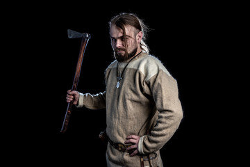 Young bearded man in a viking age clothing with an ax
