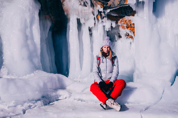 Traveling woman sitting in front of frozen waterfall. Winter tourism in Russia Baikal Lake. © flying creature