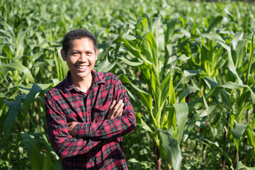 Asian farmer smiling and arms crossed in corn field, Thailand