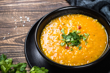 Red lentil soup in black bowl.