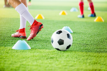 soccer player is jogging with blurry cone markers and football on  artificial turf