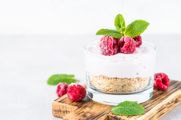 No baked cheesecake with raspberry in glass jar.
