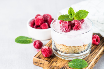 No baked cheesecake with raspberry in glass jar.