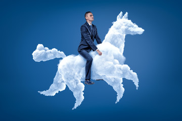 Young businessman riding white cloud horse on blue background