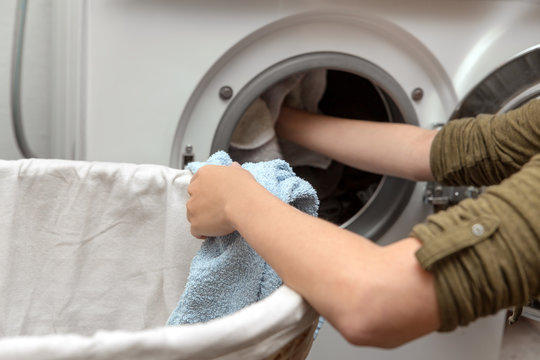 Frau legt Wäsche in die Waschmaschine, Hausarbeit