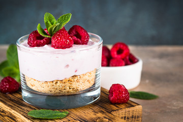 No baked cheesecake with raspberry in glass jar.