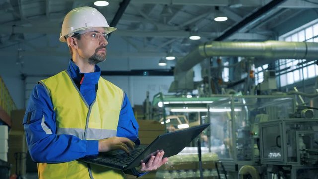 Plastic factory with a male expert operating a laptop