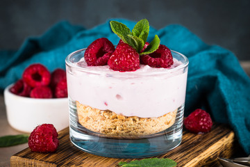 No baked cheesecake with raspberry in glass jar.