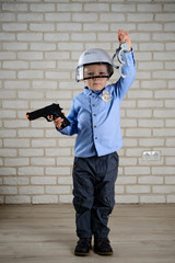 boy 4 years old plays a policeman with toy guns and handcuffs