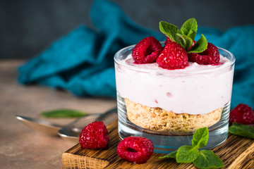 No baked cheesecake with raspberry in glass jar.