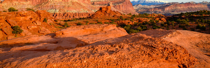 Sunset during golden hour in Southern Utah, sun warming red sandstone, cliffs, mountains, and mesa