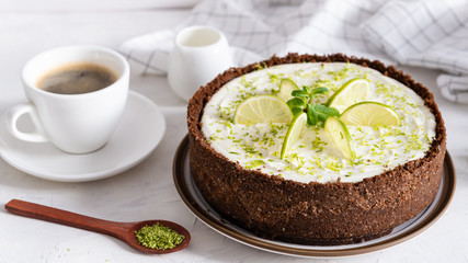 Lime cheesecake with peppermint. Cheesecake with cup of coffee on white background. Side view. Coffee house, confectionery concept, for banner