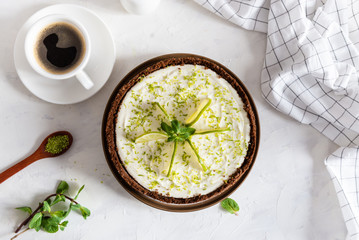 Delicious homemade cheesecake with lime and pepper mint with cup of coffee on white table, top view