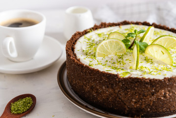 Homemade cheesecake with lime and mint for dessert - healthy organic summer dessert pie cheesecake. Cheese cake with a cup of coffee on white background