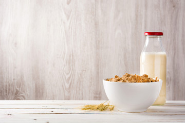 Oats milk and cereals on white wooden table