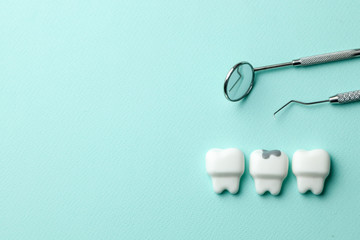 Healthy white teeth and tooth with caries on green mint background  and dentist tools mirror, hook....