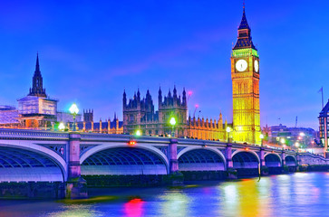 Naklejka premium View of the Houses of Parliament and Westminster Bridge along River Thames in London at night.