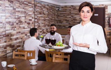 Smiling female waitress bringing order for guest