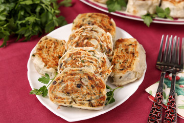 Fried lavash rolls with potatoes and mushrooms are located on a plate