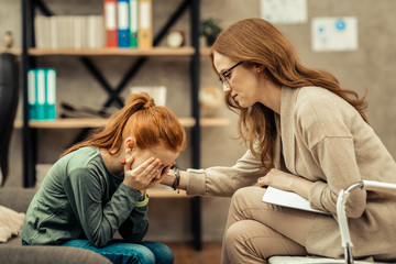 Unhappy pleasant young girl covering her face