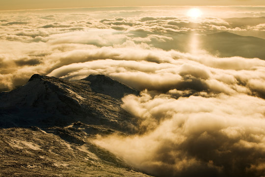 The Appalachian Mountain Club's Late Tear of the Clouds Hut  at a sunset over an undercast with the peak of Mt. Monroe behind it.