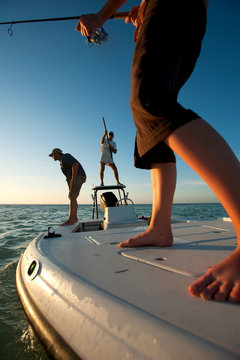 Anna Carradice-French casts her line as Garry Turner watches and Chris Robinson pilots the boat off of Key West, Florida.