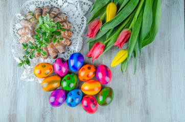 colorful easter eggs, easter cake and tulips on wooden table