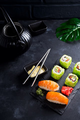 Various Fresh and delicious sushi set on black slate with slate sticks, sauce and nori on black stone background , flat lay
