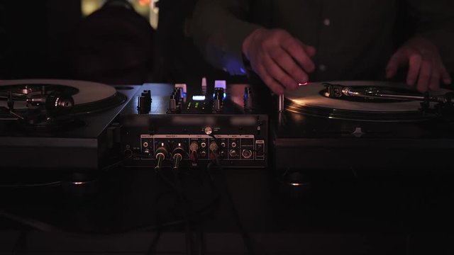 DJ plays vinyl turntables. In a nightclub - bar. The vinyl record is spinning.