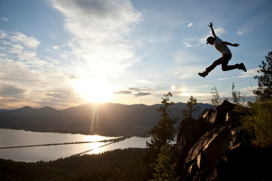 Young man soaring at sunset next to a large cliff overlooking Lake Pend Oreille and Sandpoint, Idaho.