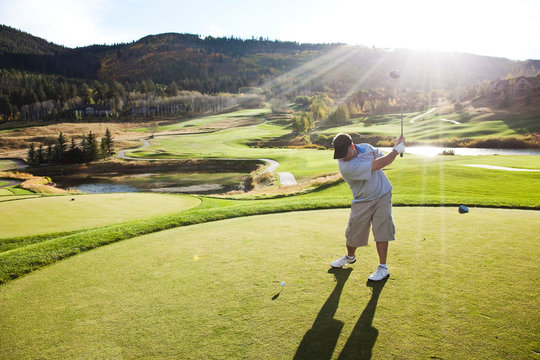 A male golfer hitting a golf ball at sunset