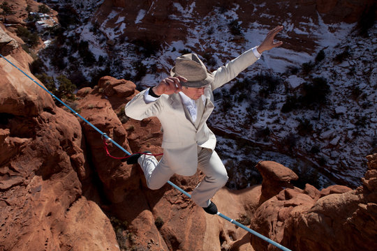 Male highliner in white pinned stripe suite, Moab, Utah, USA.