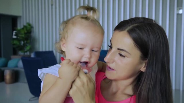 mom gives daughter a pacifier and the baby sucks her, how to wean her nipples, slow motion.